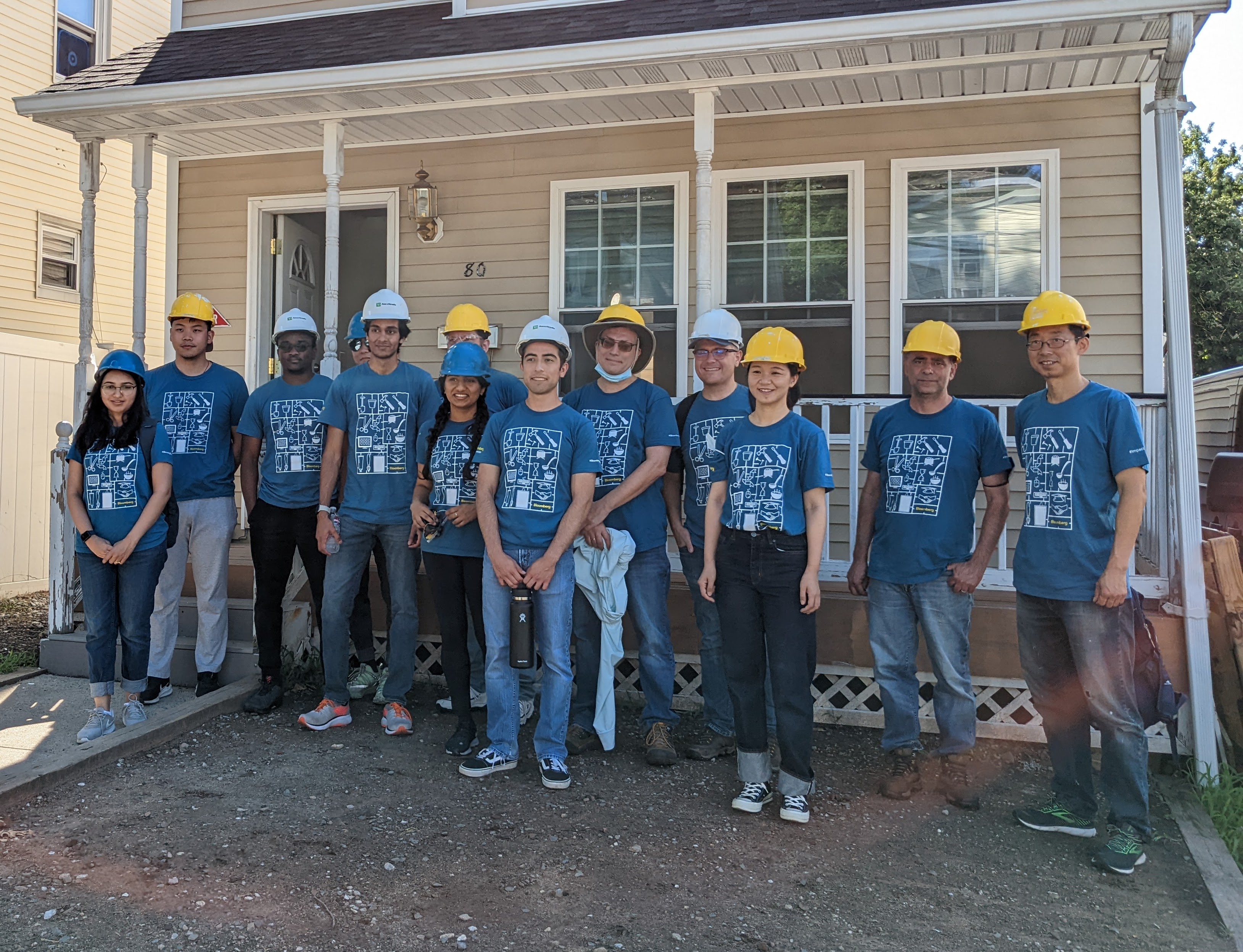 Bloomberg volunteer team in hard hats in front of a Habitat for Humanity build site